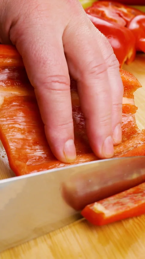 Chef slices fresh red bell pepper into strips on a wooden cutting board. Stock Footage 342283065