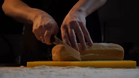 Chef slices freshly baked bread in the kitchen. Eco-friendly product Stock Footage 121312801