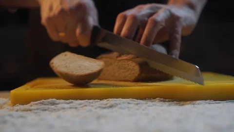 Chef slices freshly baked bread in the kitchen. Black fresh bread Stock Footage 121312825