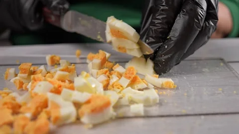 The chef slices hard-boiled eggs for the olivier salad. High quality 4k footage Stock Footage 291683122
