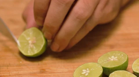 Chef Slices Key Limes on a Bamboo Cutting Board Stock Footage 62748059