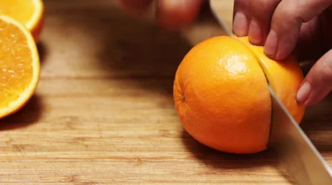 Chef Slices an Orange on a Bamboo Cutting Board Stock Footage 62746513