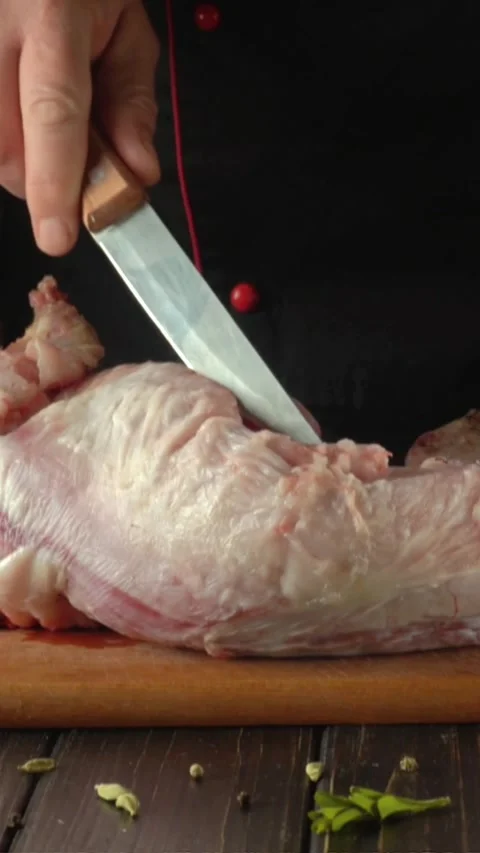 Chef slices raw meat with a sharp knife on a wooden cutting board, surrounded by Stock Footage 339778214
