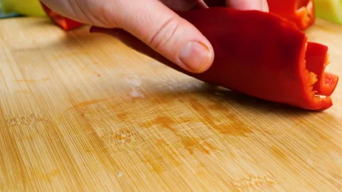 A chef slices ripe red bell pepper on a wooden cutting board. 库存影片 341555972