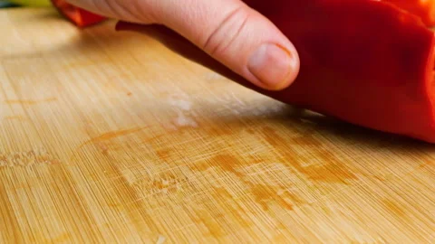 A chef slices ripe red bell pepper on a wooden cutting board. 库存影片 342286756