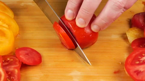 A chef slices ripe red tomatoes on a wooden cutting board with a sharp knife.  스톡 동영상 342286129
