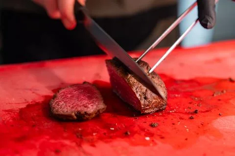 Chef slices seared beef on red board in Oberlech, Austria kitchen Stockfoto's