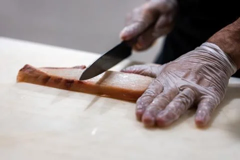 Chef slices translucent fish fillet on board, Maldives kitchen scene 写真素材