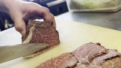 Chef Slicing A Block Of Marbled Roast Beef With A Knife On A Cutting Board Stock-Footage 338204039