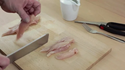 Chef slicing a breast of chicken with a cleaver knife on a chopping board Stock-Footage 62412917