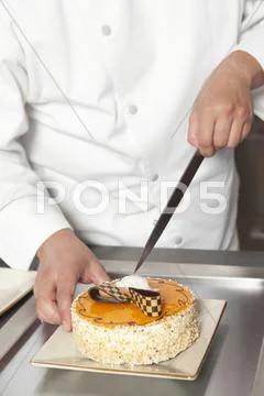 Chef Slicing Cake At Counter In Commercial Kitchen Stock Photos