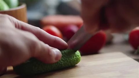 Chef slicing cucumber with knife on cutting board extreme close up Stock Footage 120912879