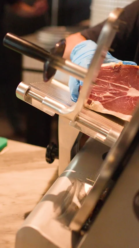 Chef Slicing Cured Ham with Professional Meat Slicer in Kitchen Stock Footage 338321770