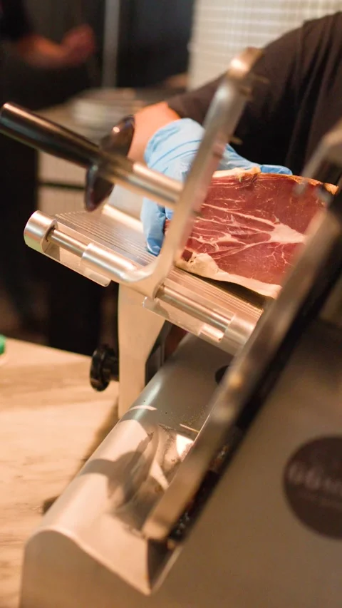 Chef Slicing Cured Ham with Professional Electric Meat Slicer Stock Footage 339540147