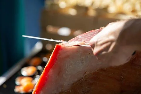 Chef slicing cured ham with sharp knife 库存照片