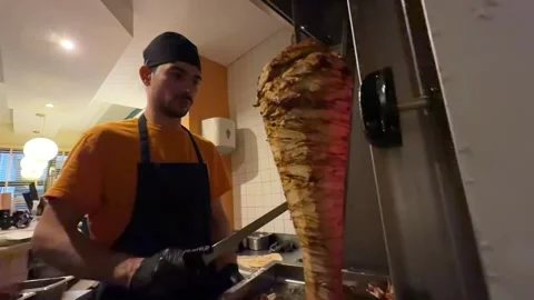 Chef slicing doner kebab meat at restaurant Видео 336232906