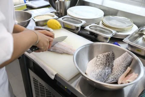 The chef is slicing the fish on a white plastic chopping board to prepare to  Stock Photos