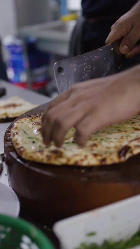 Chef Slicing Fresh Baked Naan Bread with Cleaver Stock Footage 345714952