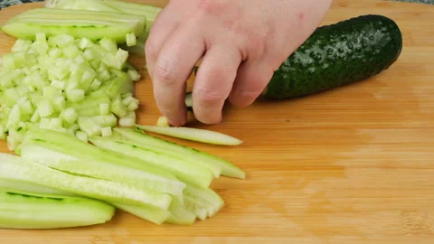 A chef is slicing a fresh green cucumber with a sharp knife. 스톡 동영상 341546799
