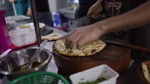 Chef Slicing Fresh Naan Bread with Cleaver on Wooden Board Stock Footage 345710384