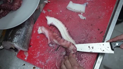 Chef slicing a fresh octopus tentacle on a cutting board Video stock 323792403