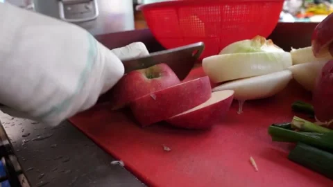 Chef Slicing Fresh Red Apple and Onions on Red Cutting Board Video stock 343588031