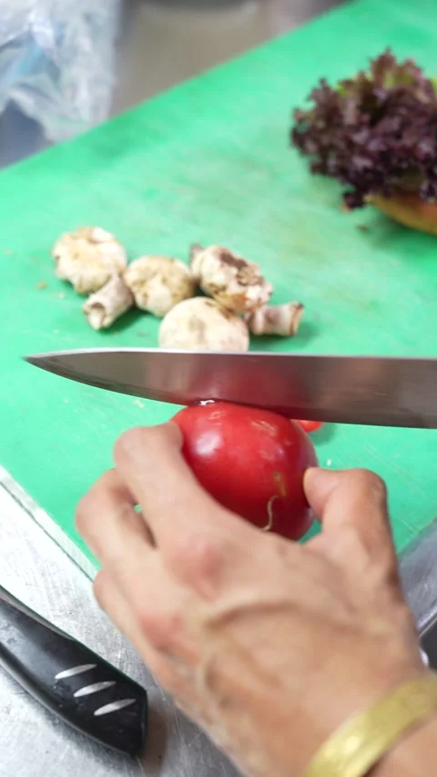 Chef slicing fresh red tomato on wooden cutting board in kitchen Stock Footage 340398231