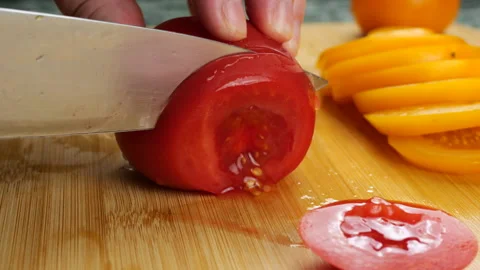 Chef slicing fresh ripe red and yellow tomatoes on a wooden cutting board. 스톡 동영상 341472384
