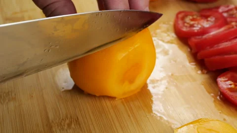 Chef slicing fresh ripe red and yellow tomatoes on a wooden cutting board. Stock Footage 341472548