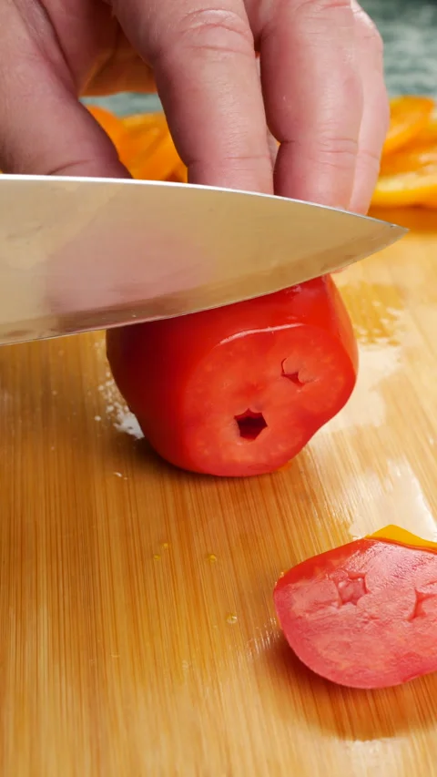 Chef slicing fresh ripe red and yellow tomatoes on a wooden cutting board. 库存影片 341474859