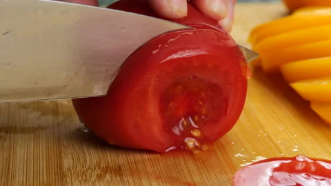 Chef slicing fresh ripe red and yellow tomatoes on a wooden cutting board. Stock Footage 342279972