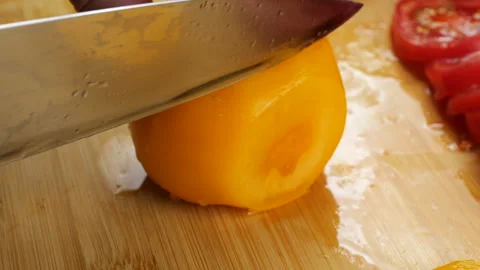 Chef slicing fresh ripe red and yellow tomatoes on a wooden cutting board. Stock-Footage 342279989