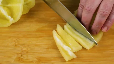 Chef slicing fresh yellow bell pepper on wooden cutting board. 스톡 동영상 341554866