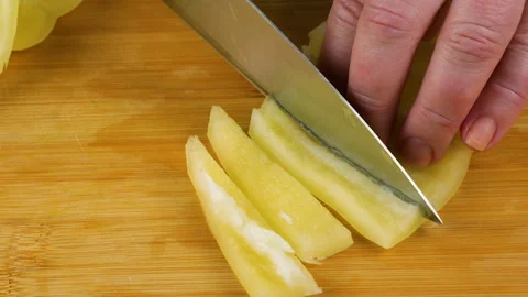 Chef slicing fresh yellow bell pepper on wooden cutting board.  Video stock 342286529