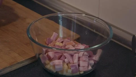 Chef slicing garlic and adding it to a bowl with diced ham and cheese Stock Footage 337622208
