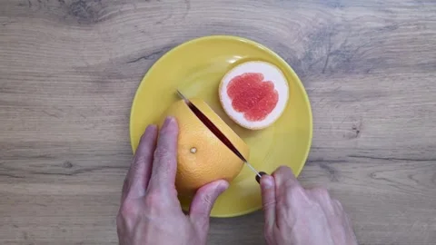 Chef slicing grapefruit on yellow plate Vídeo Stock 317577609