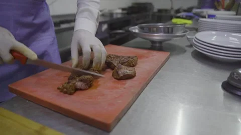 Chef slicing grilled steak on cutting board in restaurant kitchen Stock Footage 332116302