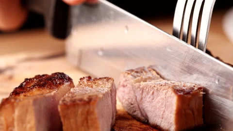 Chef slicing medium or well done beef steak with knife and fork Stock Footage 222778766