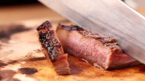 Chef slicing medium or well done beef steak with knife and fork Stock Footage 223176759