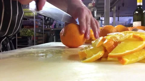 Chef is slicing oranges into half moon slices, at a restaurant kitchen Stock Footage 58112793