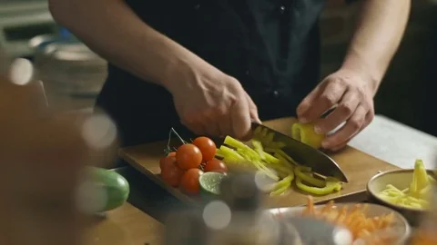 The chef is slicing pepper for the salad at the kitchen table Stock Footage 73349064