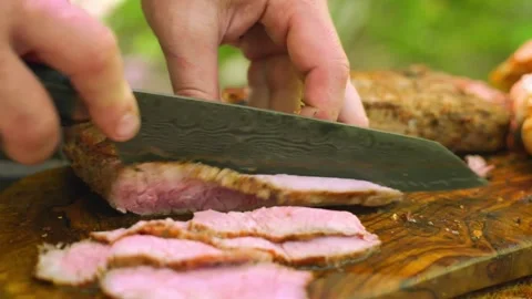Chef slicing a perfectly cooked mediumrare steak on a wooden cutting board Stock Footage 336656789