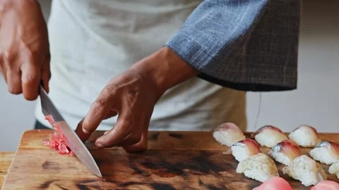 Chef slicing pickled ginger with sharp knife on wooden board next to freshly 库存影片 348742045