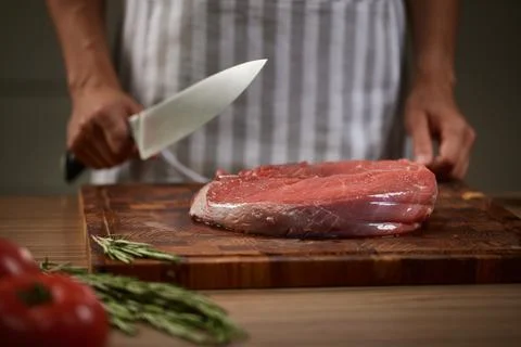 Chef slicing raw beef steak for cooking Stock Photos