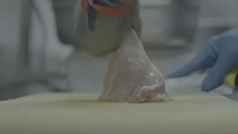 Chef slicing raw chicken with a sharp knife and chainmail glove Stock-Footage 327353682