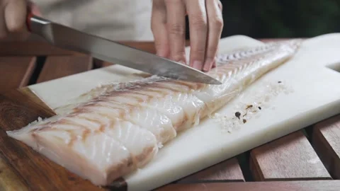 Chef is slicing raw codfish on the board Stock Footage 143778367