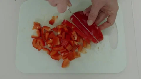 Chef slicing red bell peppers on white cutting board Stock Footage 312659044