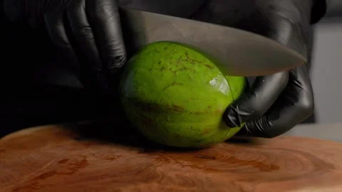 Chef slicing ripe avocado in half on wooden board with sharp knife Video stock 313028903