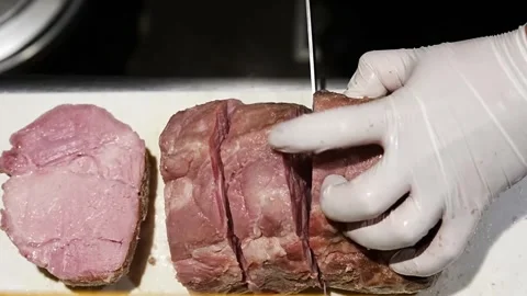 Chef slicing roasted meat into thick portions on board Stock Footage 345930340