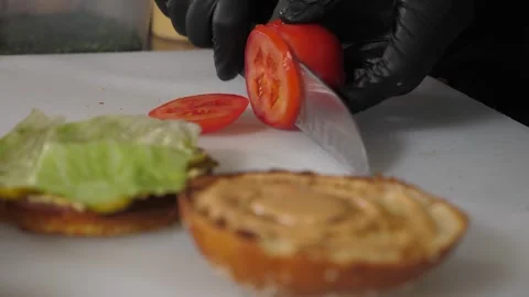 Chef slicing a tomato for a burger in the kitchen, process of cooking a burger. Stock Footage 342702511